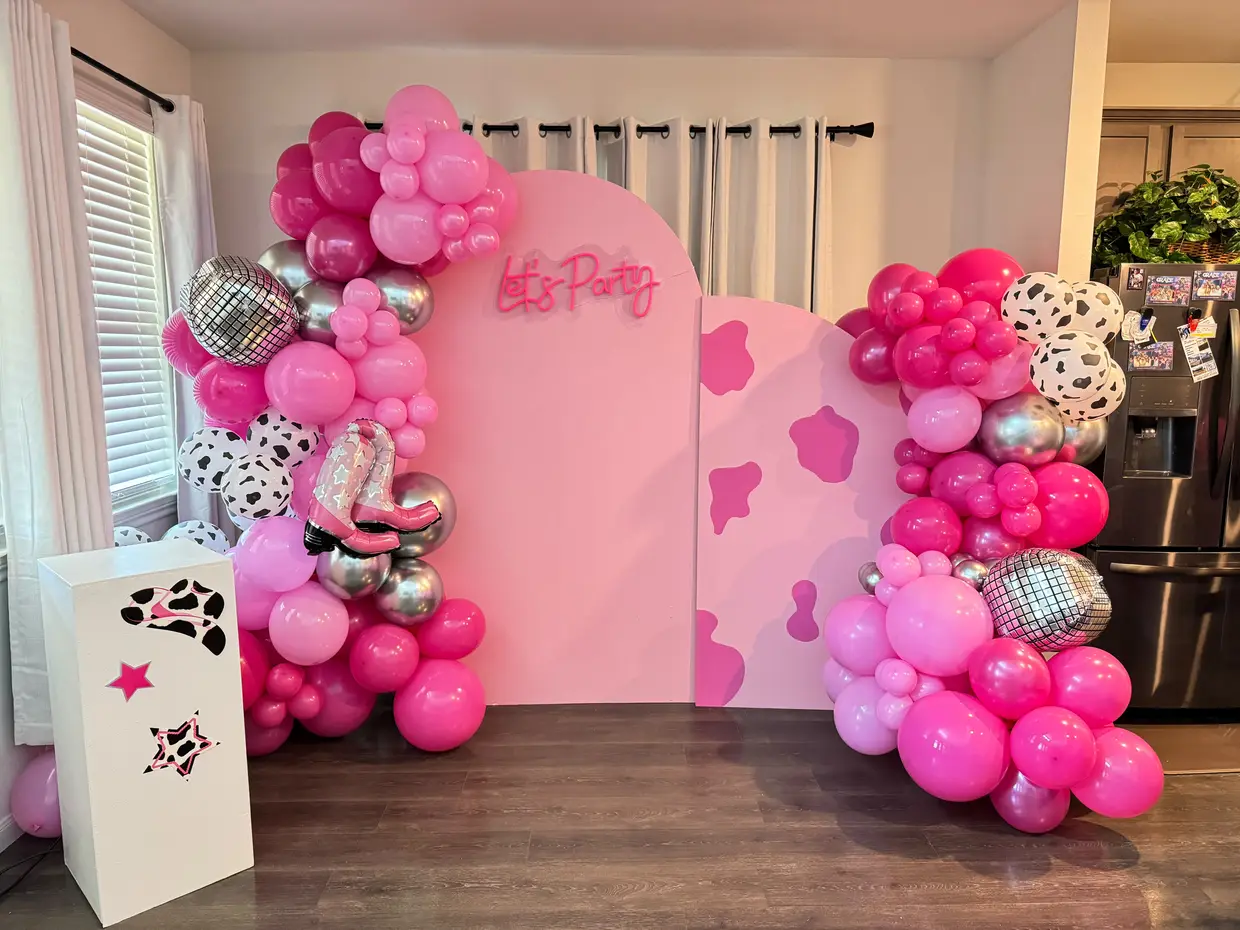 Pink cowgirl balloon arch with a Let's Party neon sign and disco balloons